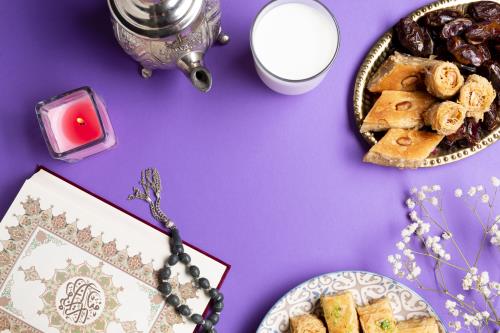سفره افطار به همراه قرآن کریم و چای و شیر و شیرینی و خرما و تسبیح با تصویر زمینه بنفش