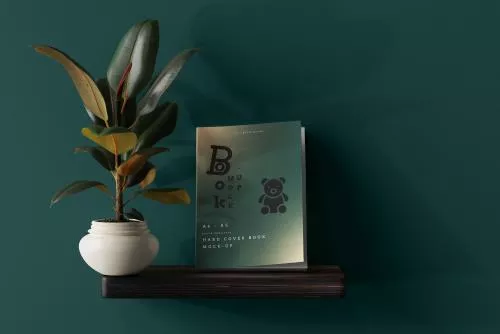 موکاپ کتاب از زاویه رو به رو روی سطح در کنار گلدان با نوردهی حرفه ای و تارک mockup با فایل PSD لایه باز با لایه بندی حرفه ای	