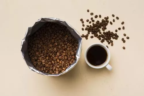 چیدمان دانه های قهوه سیاه در زمینه بژ با فنجان قهوه 22099